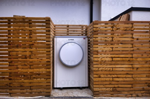 Bosch Compress 7400i AW air-to-water heat pump, logo, outdoor unit, building services, standing in front of garden fence, wooden fence, recess, Stuttgart, Baden-Württemberg, Germany, Europe