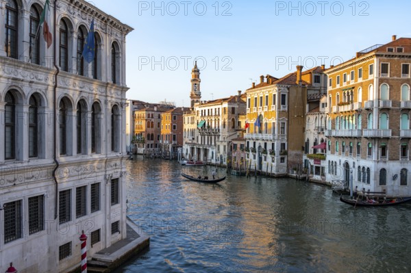 View of the Grand Canal with gondoliers at sunset, picturesque evening mood with palazzos on the canal and church tower of the Chiesa Parrocchiale dei Santi Apostoli, view from the Rialto Bridge, Venice, Veneto, Italy, Europe