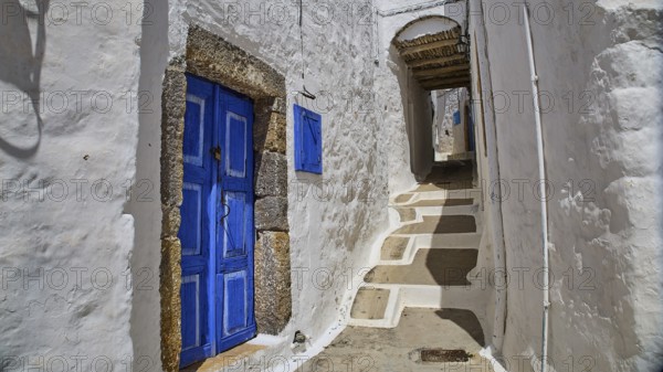 Narrow, sunny alley with blue doors in traditional white Mediterranean architecture, Mantomata stones, Chora, UNESCO World Heritage Site 1999, Patmos, Dodecanese, Greek Islands, Greece, Europe