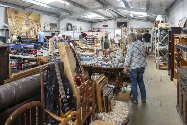 People at auction viewing inside auction room of household clearance lots, Suffolk, England, UK
