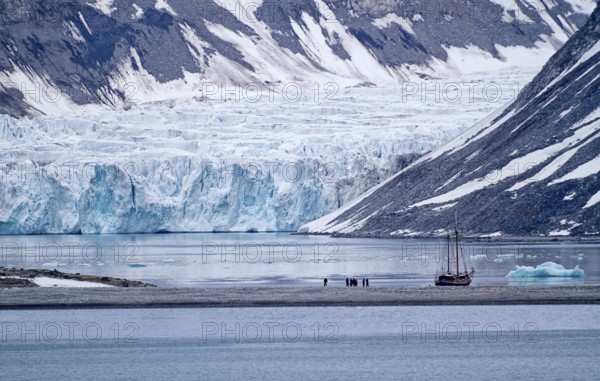 A sailboat in front of a glacier in a cold and calm arctic landscape, Magdalenenfjord with Waggonway Glacier, Spitsbergen, Norway, Europe