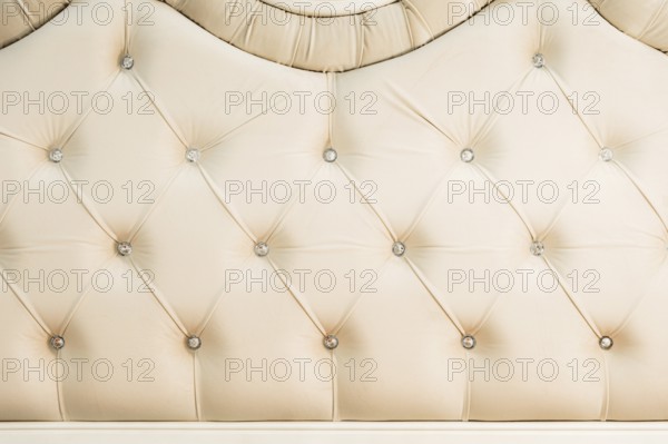 Beige soft textile background with symmetrical buttons on the corners of diamonds. Soft and expensive furniture elements. Luxury background