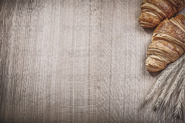 Golden wheat rye ears croissants on wooden board copyspace