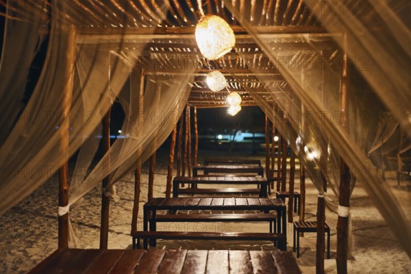 Empty beach restaurant lounge bar with lantern in the evening on tropical island. Summer vacation, romantic dinner concept