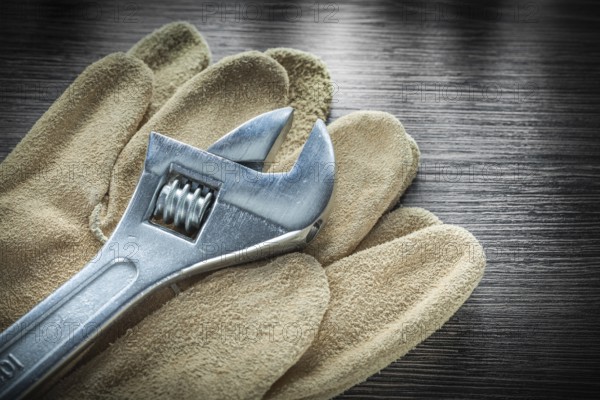 Adjustable spanner Protective leather gloves on wooden board