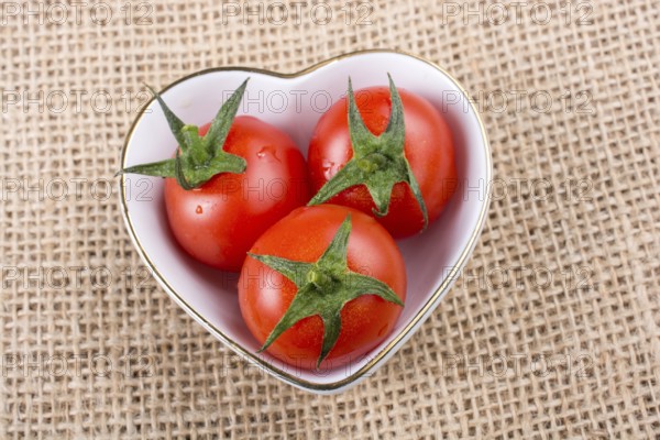 Red ripe cherry tomatos tomatos in heart shaped bowl