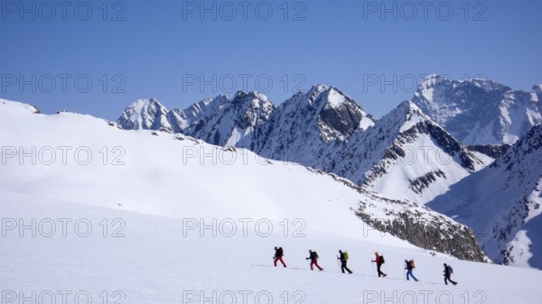 group of backcountry skiers crossing a glacier on their way to a high summit in the Alps of Switzerland near Disentis