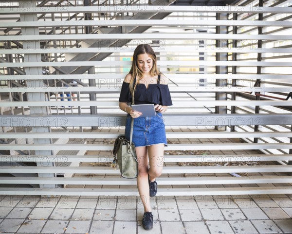 Young woman with bag using tablet university
