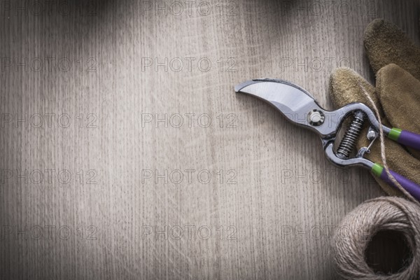 Brown leather gardening gloves secateurs and rope on wooden board copy space image agriculture concept