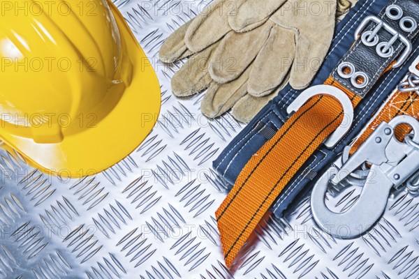 Yellow helmet, safety harness and gloves on corrugated metal plate