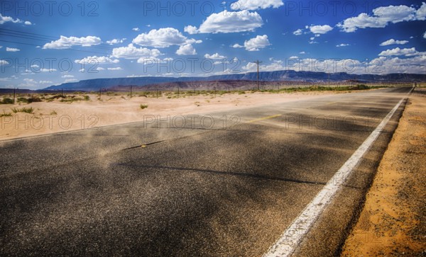 black asphalt highway with wind gust blowing red sand across inthe northern Arizona desert in the middle of nowhere