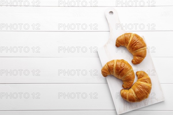 Traditional french croissant on white wooden table, tasty breakfast