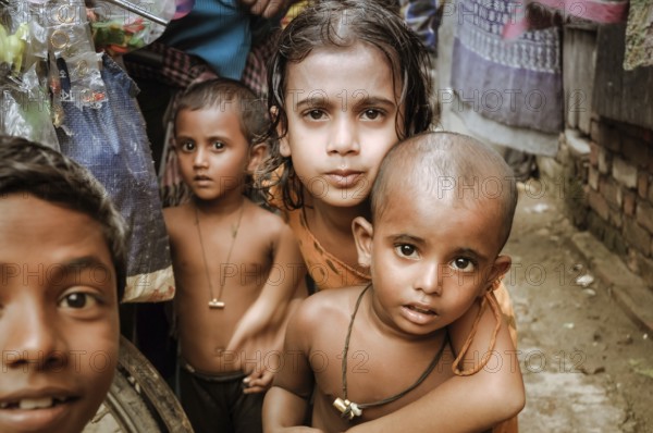 Khulna, Bangladesh, circa July 2012: Young native children with brown hair and brown eyes look curiously to photocamera in slum in Khula, Bangladesh. Documentary editorial, Asia