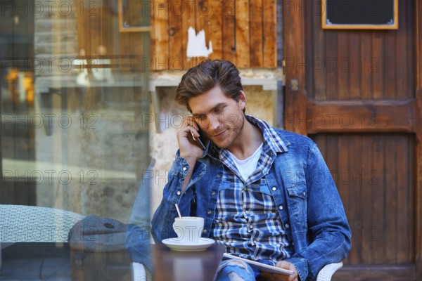 Young man with smartphone in an cafe outdoor sitting