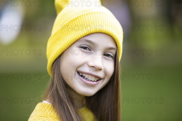 Beautiful teenage girl wearing braces smiling happily dressed in bright yellow clothes outdoors. Cute and happy teenage girl with braces smiling to camera. Alignment biting teeth, correct teeth biting