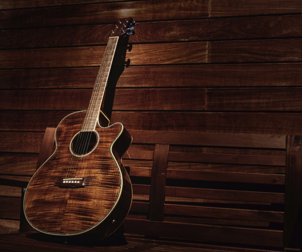 Acoustic brown guitar in a wooden stripes wooden wall monochromatic