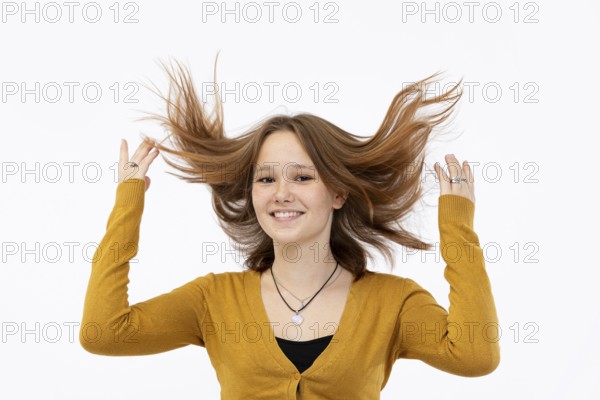 A cheerful girl enjoys her vibrant hair, complemented beautifully by her bright yellow sweater that stands out