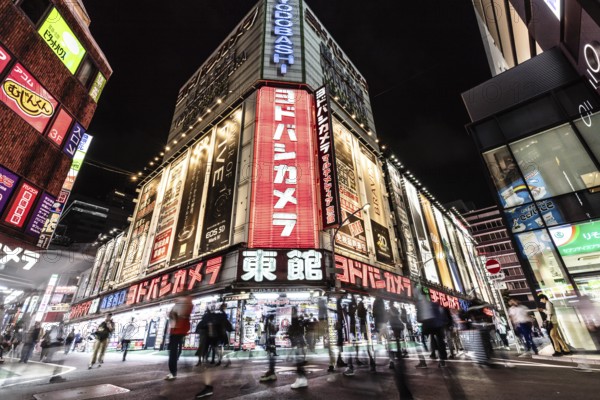 TOKYO, JAPAN - MAY 18 2019: Neon signs illuminate Tokyo's busy Shinjuku neighborhood at night around Yodobashi camera store