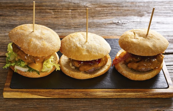 Burger in a row on a slate board and wood table