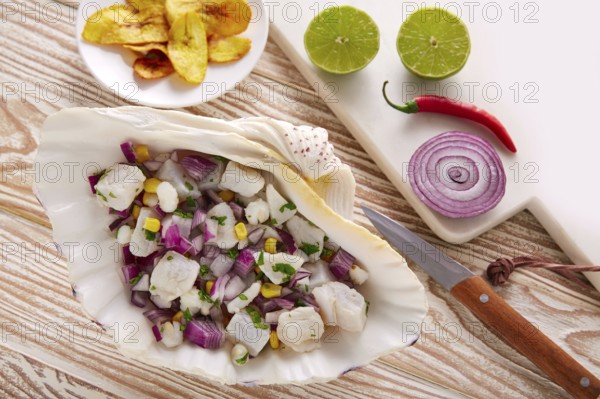 Ceviche peruvian recipe with fried banana and ingredients on wooden table