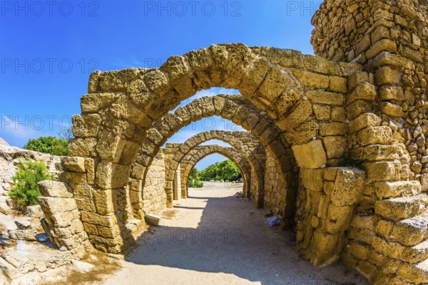 Excursion to the Archaeological Park of the Roman Empire. Arched passage - covered street of Port of Caesarea. Sunny spring day. Israel. Concept of ecological and historical tourism