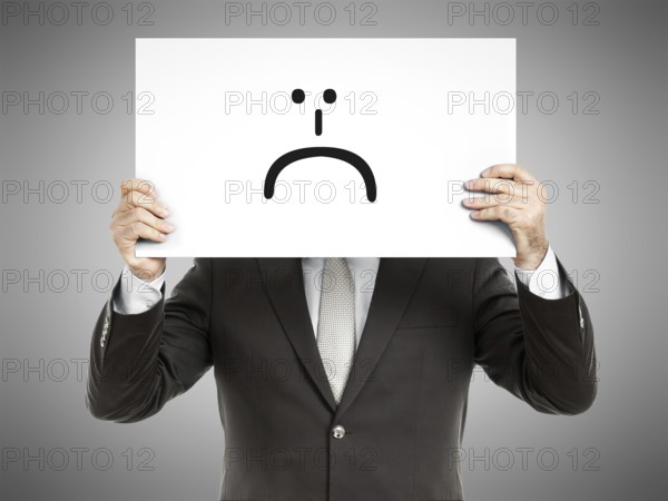 A business man holding a paper in front of his face with a smiley sign on it