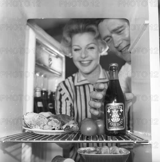 In the kitchen 1950s. A couple in their kitchen and at the refrigerator where the food and beer is kept. Sweden 1959. Kristoffersson ref CH73-1