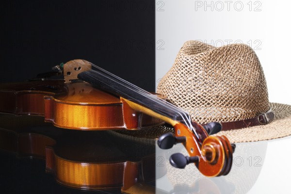 Old violin and straw hat isolated on black and white background and glass desk