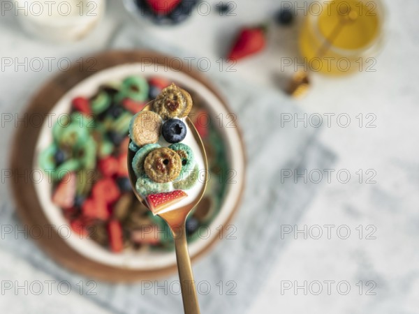 Trendy food - pancake cereal. Bowl of colorful mini cereal pancakes in spoon with milk. Tiny pancakes with natural color - green matcha, turquose spirulina, blue pea, red fragon fruit. Copy space