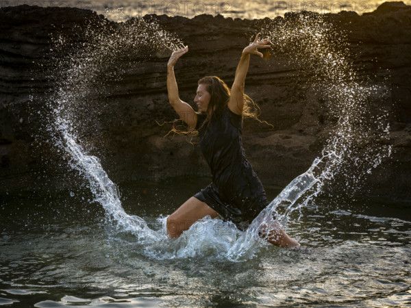 Middle-aged woman dancing and throwing water in the air, Maioris beach, llucmajor, Majorca, Balearic Islands, Spain, Europe
