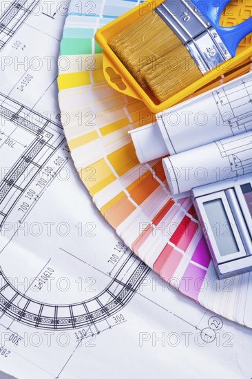 Rolled blueprints and paint brushes in tray calculator on color palette