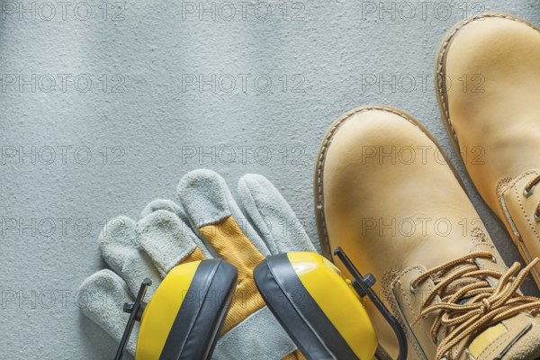 Safety lace boots protective gloves earmuffs on concrete background