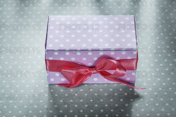 Pink present box on blue polka-dot tablecloth holidays concept