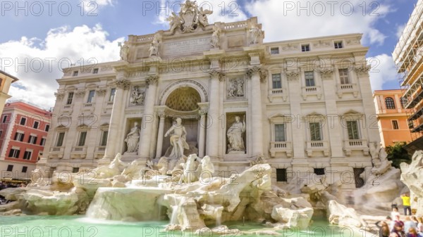 Tourists and people walking next to the Trevi Fountain in a sunny day with clouds, one of the most famous fountain in the world. Rome, Lazio, Italy, Europe