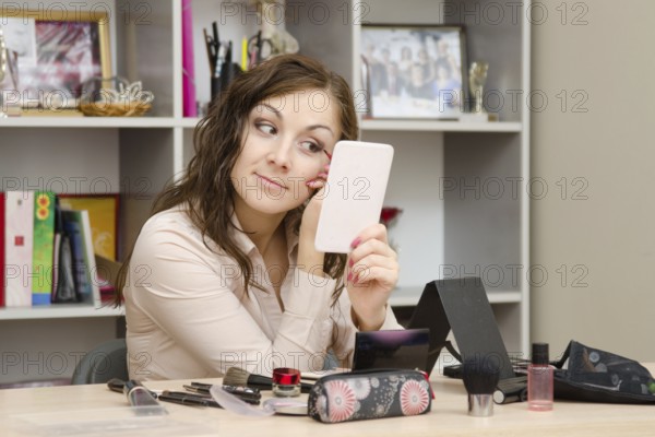 A young girl puts makeup in the office workplace