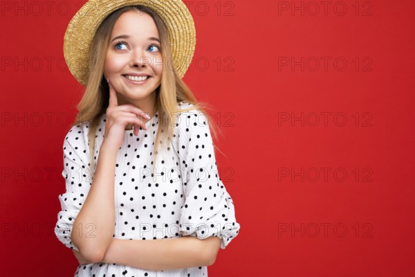 Foto-Porträt von jungen schön niedlich glücklich blonde Frau tragen lässiges Kleid und Strohhut isoliert über roten Hintergrund mit Kopierraum