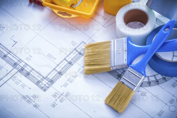 Blueprint with paint roller tray brushes bottle duct tape and wooden meter copy space image construction concept
