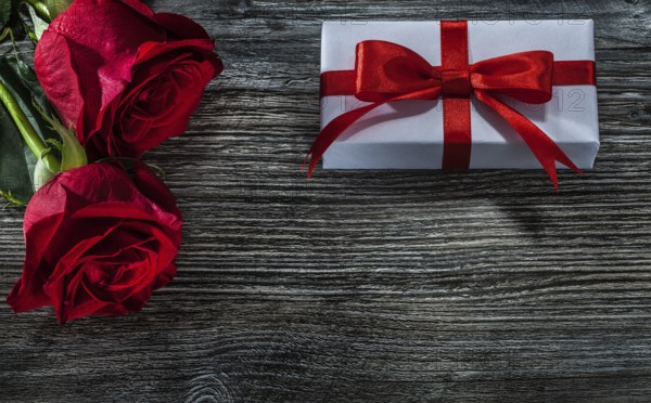 White gift boxes red roses on wooden board