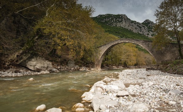 Ancient, stoned, arched bridge St. Vissarion on the Portaikos river in autumn. Trikalla pyli village Thessaly Greece