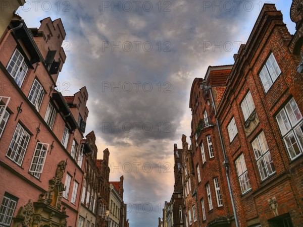 Historic red brick buildings under a dramatic cloudy sky, gothmund, travemünde, lübeck, germany
