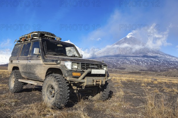 Lifted sport utility vehicle Toyota Land Cruiser Prado on background eruption active Klyuchevskoy Volcano. Car modified transmission for travel, extreme off-road trip. Kamchatka, Russia, Oct 1, 2016, Europe