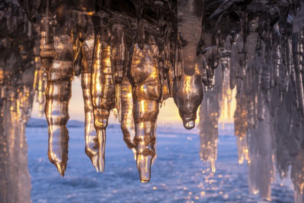 Ice cave on Baikal lake in winter. Blue ice and icicles in grotto in the sunset sunlight. Olkhon island, Baikal, Siberia, Russia, Europe