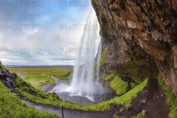 Seljalandsfoss waterfall in July. Passage under the waterfall. Sunny day in Iceland. Photo taken fisheye lens