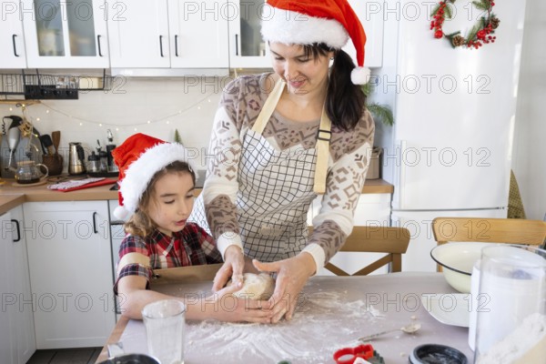 Mom and daughter in the white kitchen are preparing cookies for Christmas and new year. Family day, preparation for the holiday, learn to cook delicious pastries, cut shapes out of dough with molds