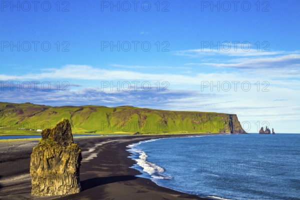 Cape Dyrholaey. The southern edge of Iceland. Beach with black volcanic ash Reinisfjara. Giant lonely rock - Palm on a black volcanic sand beach