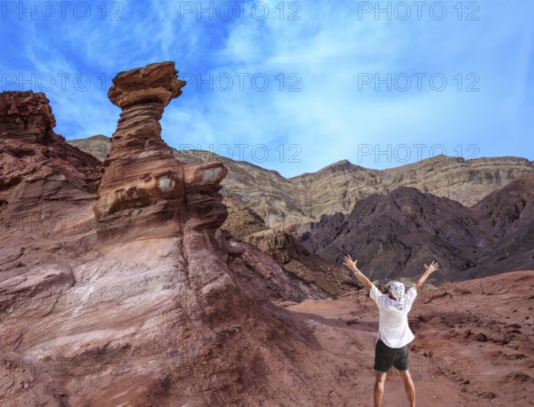 Unique outcrops in the mountains of pink sandstone. A lone tourist threw his hands up in delight in Eilat Mountains