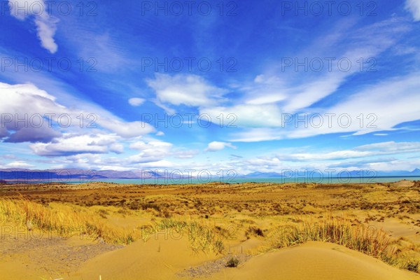 Argentine Patagonia. The endless flat prairie is overgrown with yellow autumn grass. Lake in the steppe. Whimsical clouds over the lake