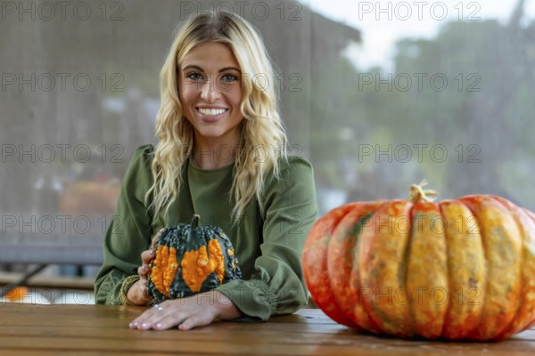 A stunning blonde model poses in a vibrant pumpkin field, wearing a stylish autumn outfit with a touch of Halloween charm. The setting glows with warm orange hues and festive seasonal vibes, New Braunfels, United States of America