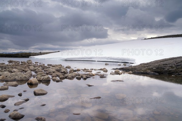 Heavily clouded sky reflecting in a lake on the Norwegian mountain plateau Aurlandsfjellet