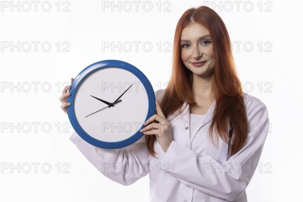 A young woman in a lab coat holds a blue clock, symbolizing effective time management and precise scheduling